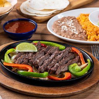Steak Fajitas at On The Border: Steak grilled over mesquite wood served sizzling alongside hand-pressed flour tortillas, pico de gallo, cheese, Mexican rice and choice of beans.