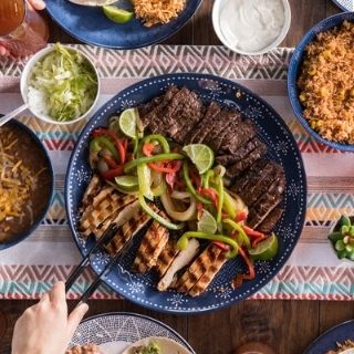 Fajita Family Meal: Mesquite-grilled chicken or steak with onions & peppers, flour tortillas, lettuce, pico de gallo, sour cream, cheese or guacamole, Mexican rice, choice of beans and chips & salsa.