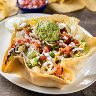 Grande Taco Salad: Ground beef or chicken tinga on a crisp blend of lettuce & shredded cabbage, mixed cheese, guacamole, lime crema, pico de gallo and pickled jalapeños. Served in a crisply tortilla shell.