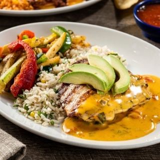 Grilled Queso Chicken: A perfectly seasoned mesquite-grilled chicken breast topped with our Signature Queso and fresh sliced avocado. Served with sautéed vegetables and cilantro lime rice.