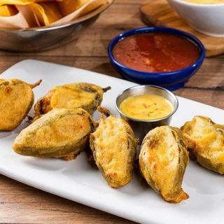 Firecracker Stuffed Jalapeños: Six handmade, tempura-fried jalapeños filled with mixed cheese and chicken. Served with our Signature Queso.