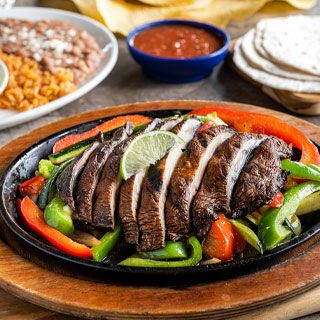 Portobello and Veggie Fajitas: Portobello mushrooms and veggies grilled over mesquite wood and served sizzling alongside hand-pressed flour tortillas, pico de gallo, cheese, Mexican rice and choice of beans.