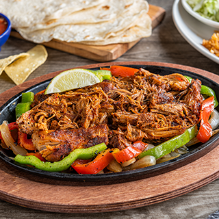 Carnitas Fajitas: Braised carnitas served sizzling alongside hand-pressed flour tortillas, pico de gallo, cheese, Mexican rice and choice of beans.